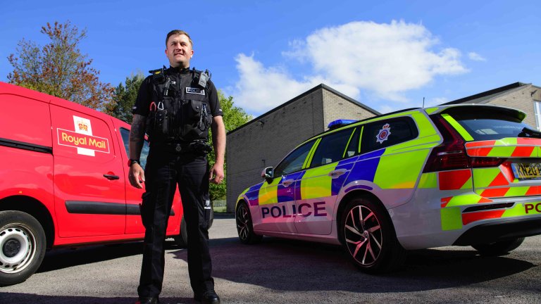 Chris Vaughan Photography - commercial photography | A special constable stands, wearing police uniform, in between a police car and his Royal Main delivery van.