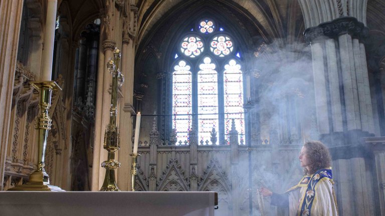 Chris Vaughan Photography - commercial photography | The Precentor is covered in smoke from the incense she is holding as she looks towards the alter.
