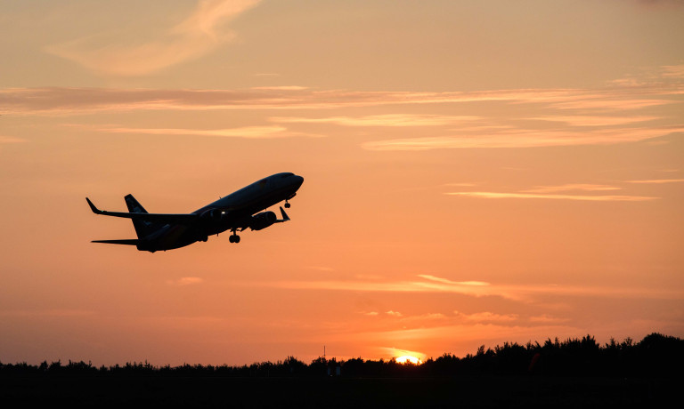 Chris Vaughan Photography - commercial photography | A plane, carry mail for the Royal Mail, is silhouette against the orange sun-setting sky, as it takes off.