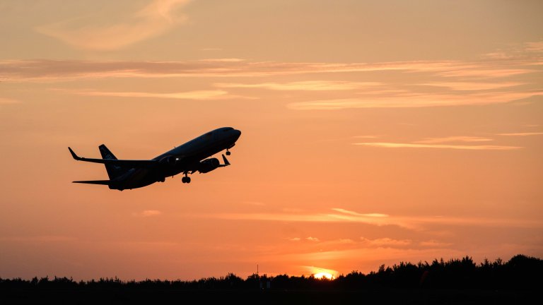 Chris Vaughan Photography - commercial photography | A plane, carry mail for the Royal Mail, is silhouette against the orange sun-setting sky, as it takes off.
