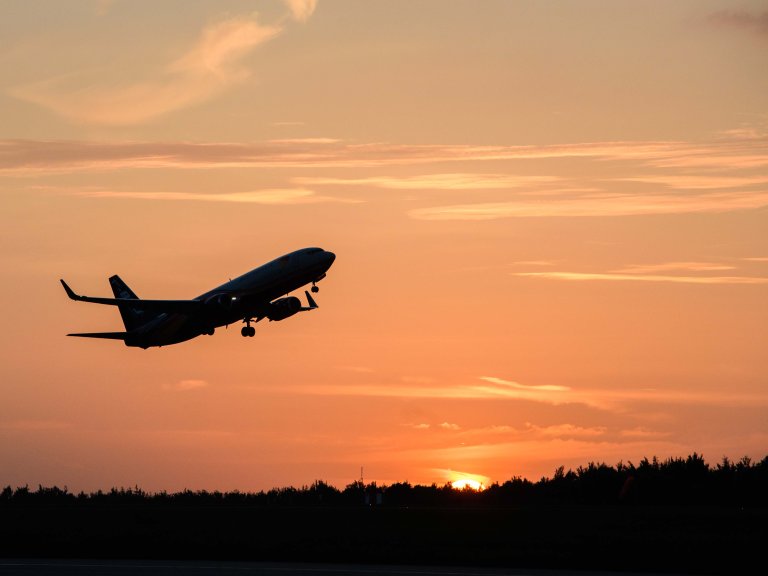 Chris Vaughan Photography - commercial photography | A plane, carry mail for the Royal Mail, is silhouette against the orange sun-setting sky, as it takes off.