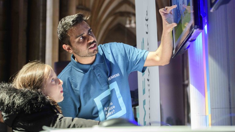 Chris Vaughan Photography - commercial photography | An engineer points out something on a screen to a young girl.