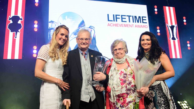 Chris Vaughan Photography - corporate event images | A couple receive a lifetime achievement award on stage.