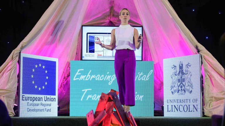 Chris Vaughan Photography - corporate event images | A speaker talks on stage which is set up as a campfire.