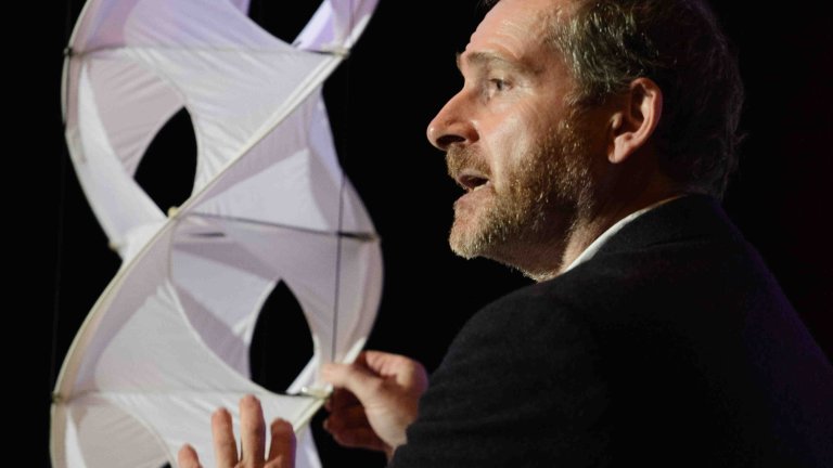 Chris Vaughan Photography - corporate event images | A speaker holds a large prop as he talks on stage.