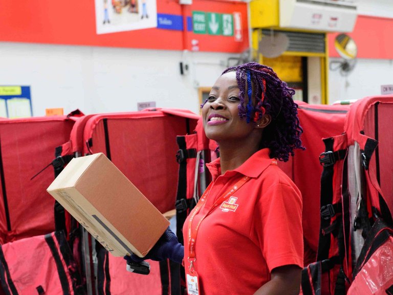 Chris Vaughan Photography - PR and communications images | A postal works sorts post in a mail centre.