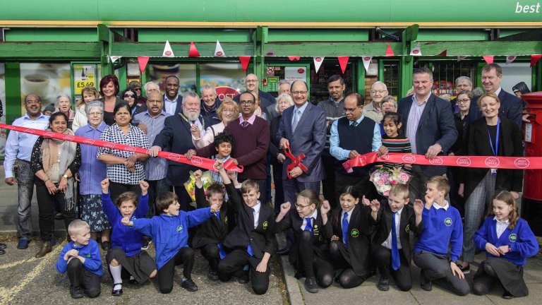 Chris Vaughan Photography - PR and communications images | Postmasters cut a ribbon, surrounded by members of the community, to celebrate the opening of their refurbished Post Office.