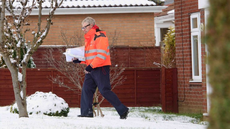 Chris Vaughan Photography - PR and communications images | A postman delivers mail in the snow.