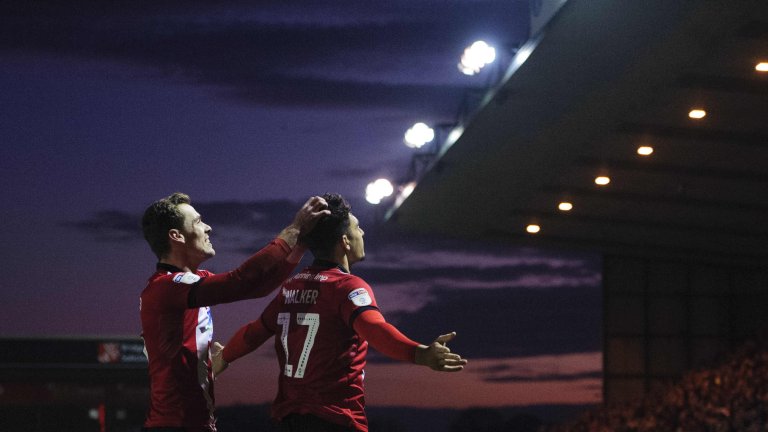 Chris Vaughan Photography - Sports images | Lincoln City players Harry Toffolo and Tyler Walker celebrate a goal as the sun sets in the background.