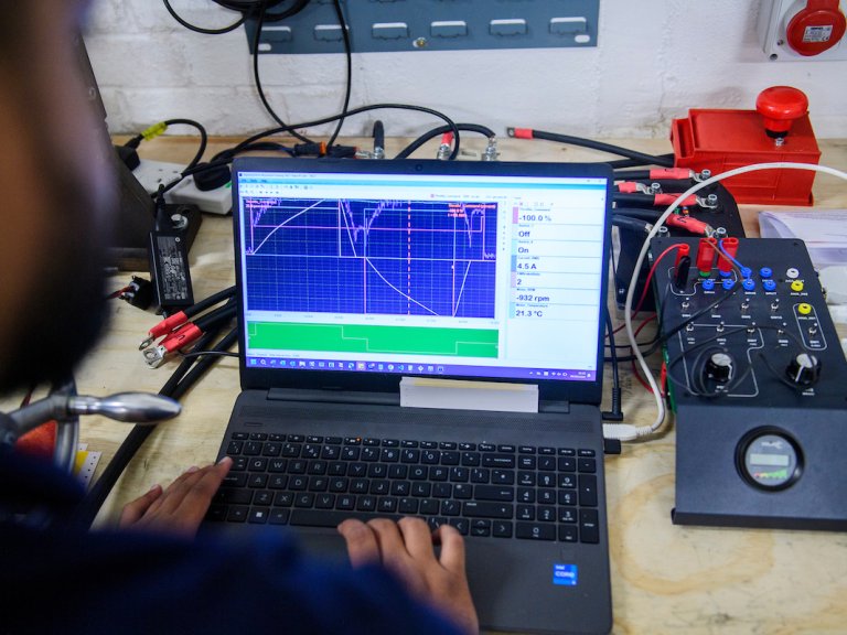 A photograph, over the shoulder of a Lancereal member of staff working on a laptop connected to equipment.