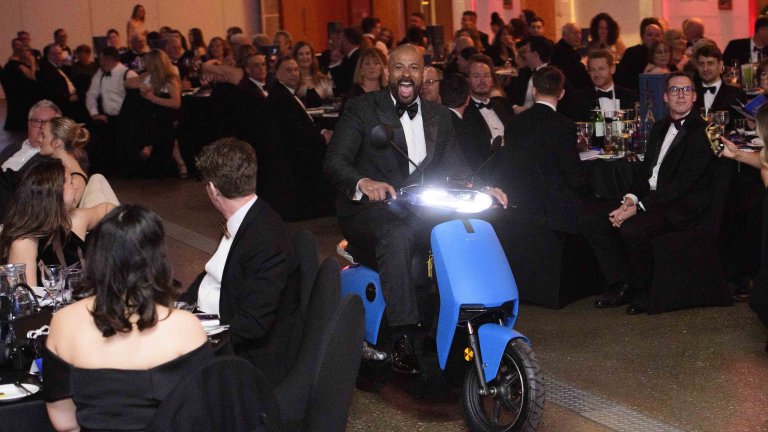 One of the hosts arrives to the event on a scooter.