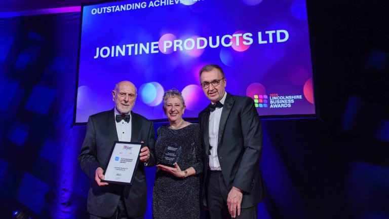 The winners of the outstanding achievement award are presented with their trophy on stage.