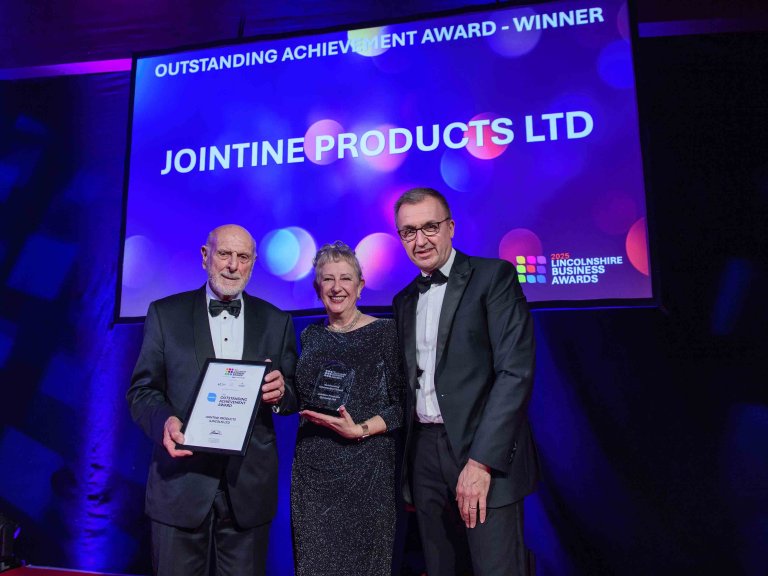 The winners of the outstanding achievement award are presented with their trophy on stage.
