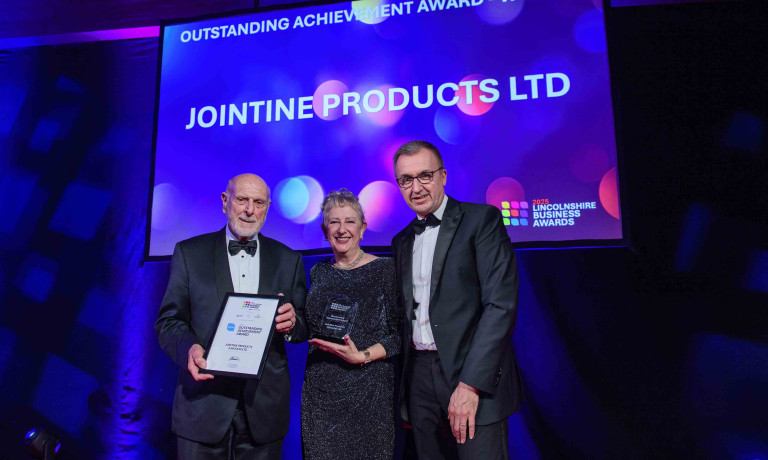 The winners of the outstanding achievement award are presented with their trophy on stage.