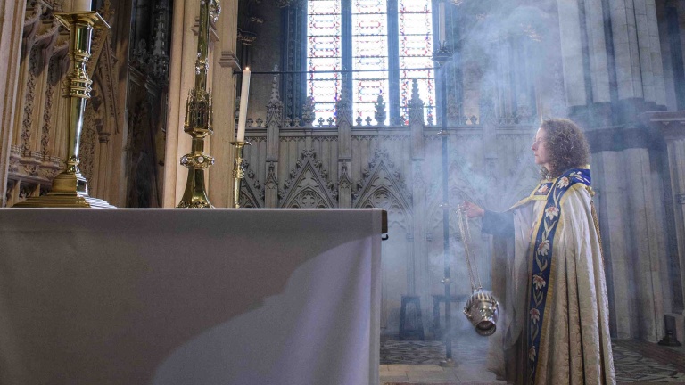 Chris Vaughan Photography - commercial photography | The Precentor is covered in smoke from the incense she is holding as she looks towards the alter.