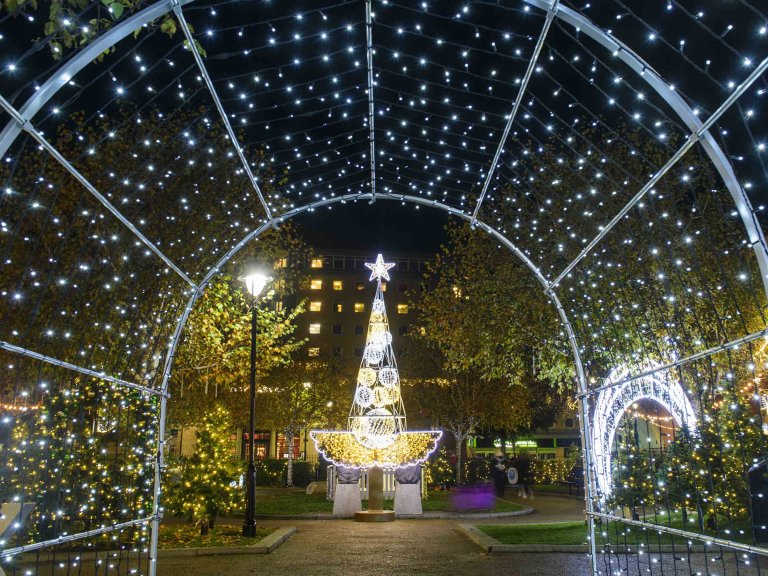 Chris Vaughan Photography - Commercial images | A modern design Christmas tree illuminated at night. The tree is framed by white Christmas lights.