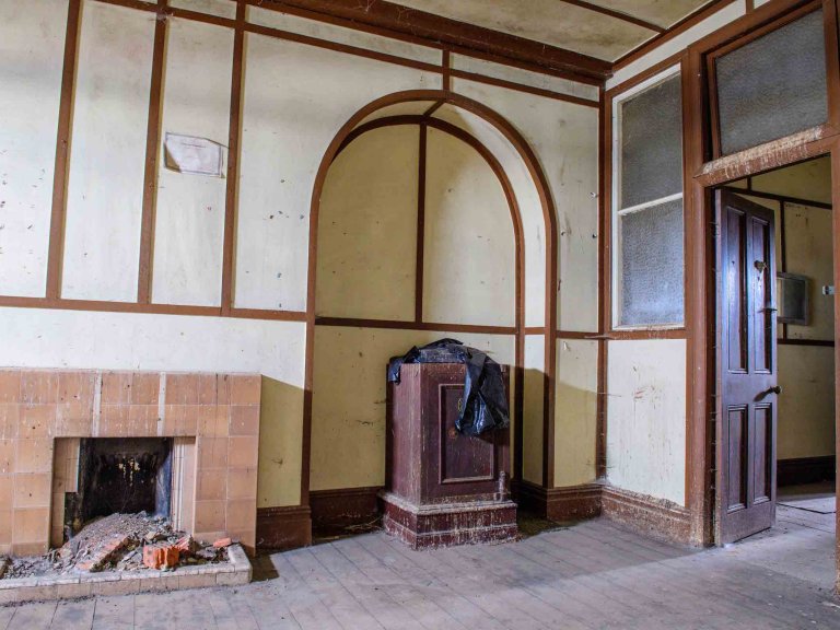 Historic interior of Building 89 with fireplaces, stove, timber framing and an arched recess.
