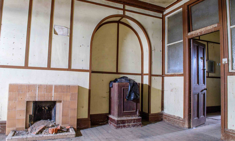 Historic interior of Building 89 with fireplaces, stove, timber framing and an arched recess.