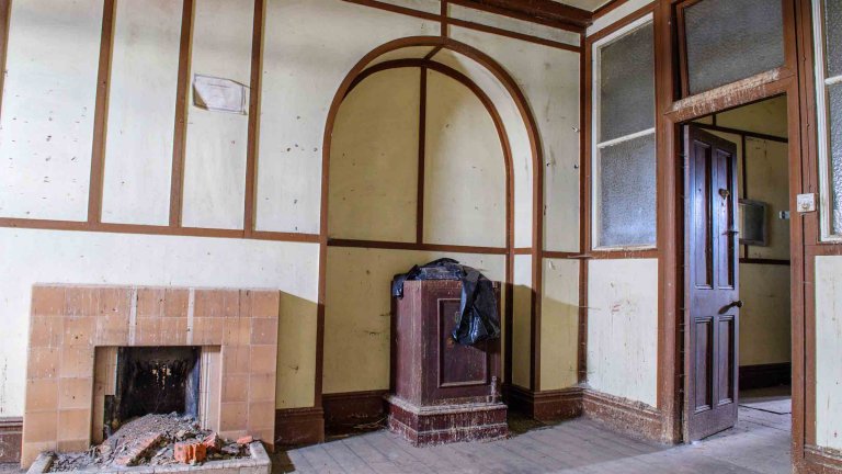 Historic interior of Building 89 with fireplaces, stove, timber framing and an arched recess.