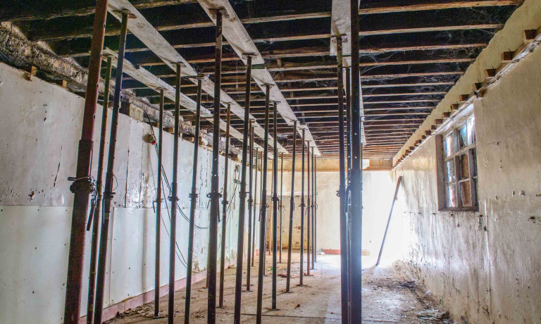 Interior of Peterson&rsquo;s Smokehouse supported by rows of temporary steel props before restoration.