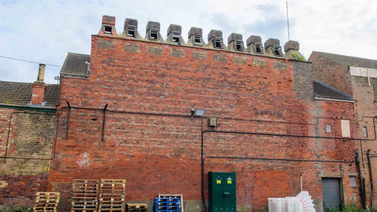 Red-brick exterior of Peterson&rsquo;s Smokehouse with its row of chimney cowls.