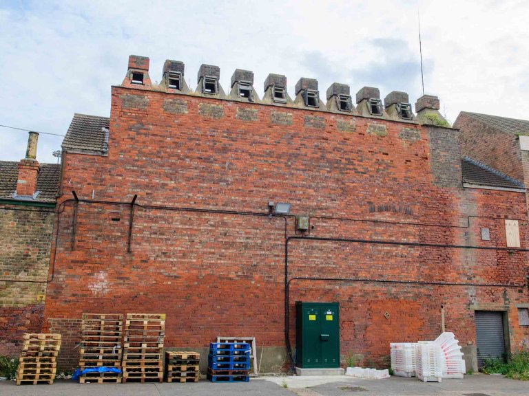 Red-brick exterior of Peterson&rsquo;s Smokehouse with its row of chimney cowls.