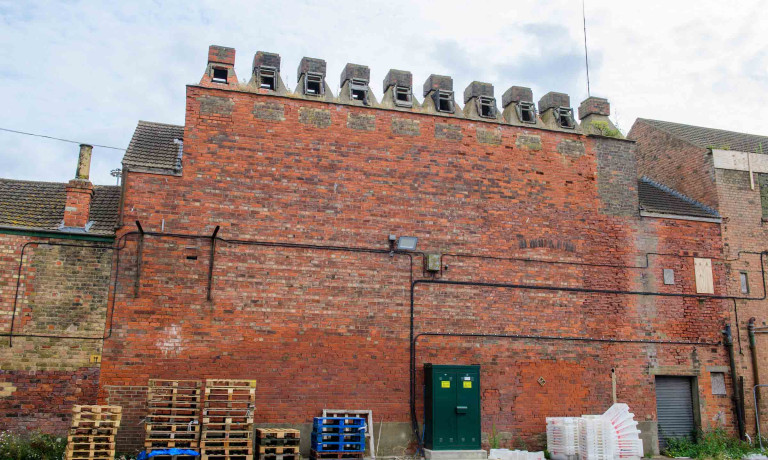Red-brick exterior of Peterson&rsquo;s Smokehouse with its row of chimney cowls.