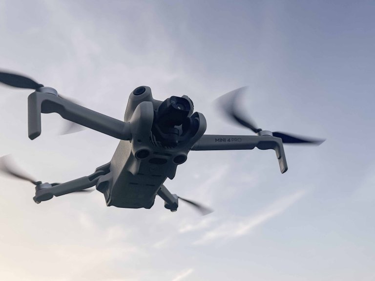 A DJI Mini 4 Pro hovering with the sky in the background.