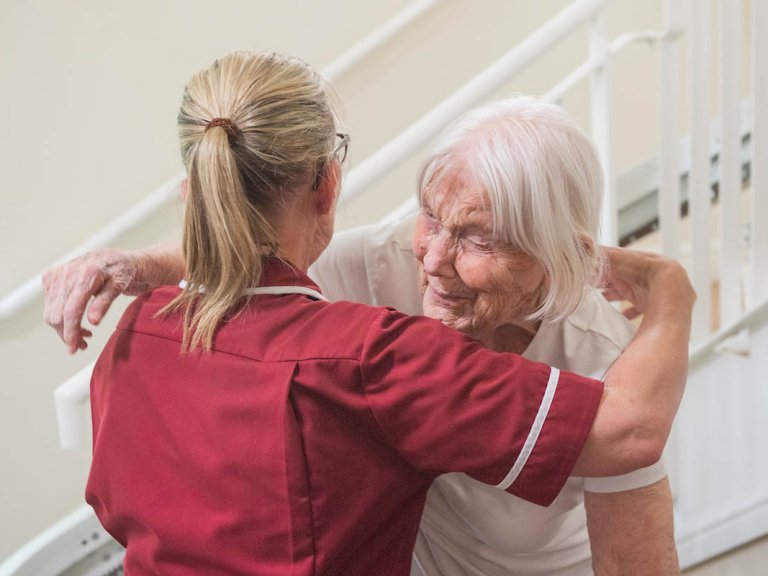 A resident hugs a carer.