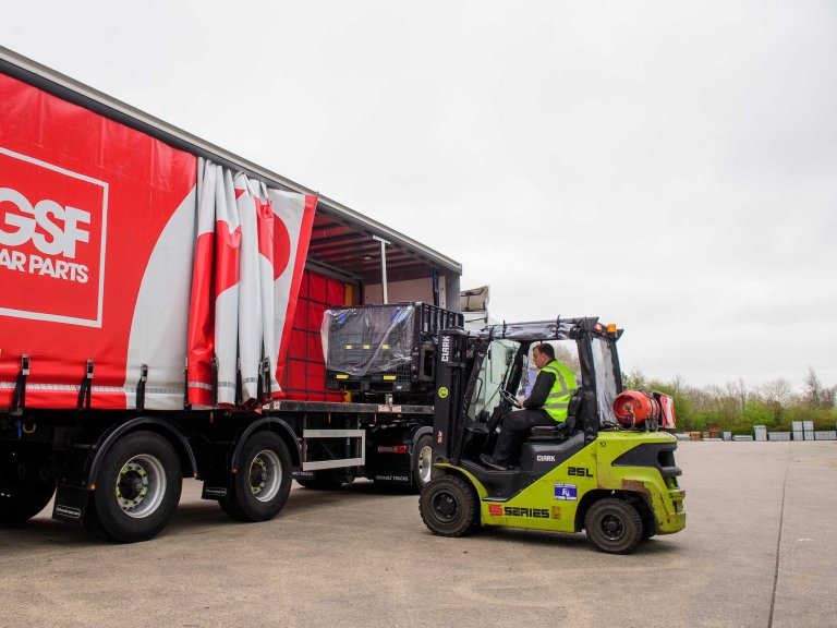 A GSF Car Parts colleague unloads items from a branded red lorry trailer using a forklift truck.