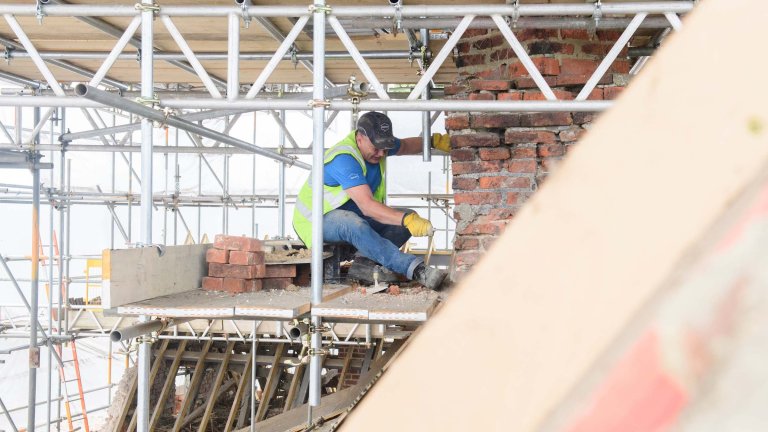 A workman working on the chimney stack of the Old Kings Head.