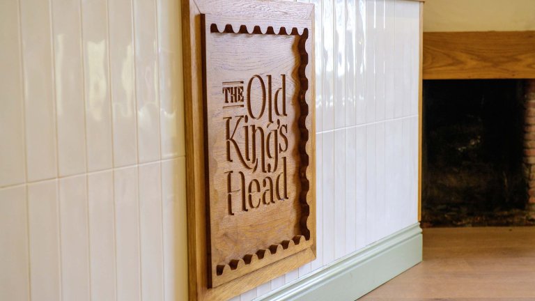 The Old Kings Head logo on the front of the serving counter in the cafe/dining area.