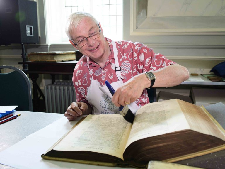 Chris Vaughan - case study images: Lincoln Cathedral | A volunteer dusts a book with a paintbrush in the Cathedral library.
