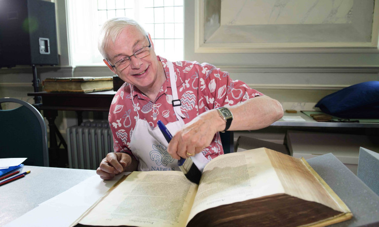 Chris Vaughan - case study images: Lincoln Cathedral | A volunteer dusts a book with a paintbrush in the Cathedral library.