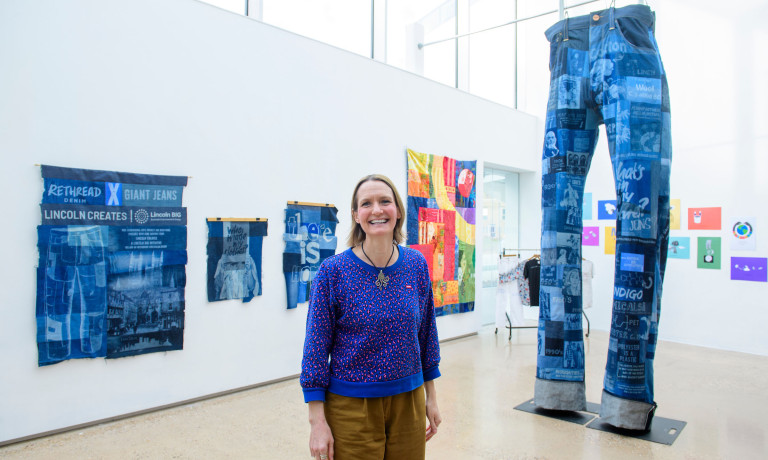 An artist is photographed in front of a giant pair of jeans she has created.