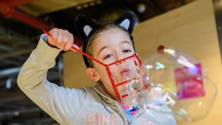Chris Vaughan - case study images: MathsCity | A youngster blows a bubble through a shape.