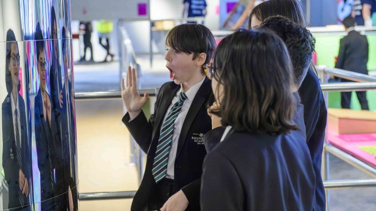 Chris Vaughan - case study images: MathsCity | Youngsters look at their reflection in a curved surface.