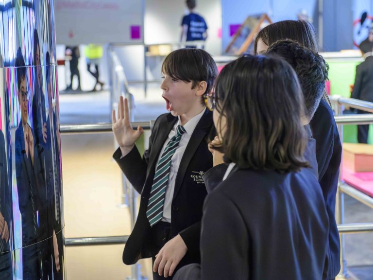Chris Vaughan - case study images: MathsCity | Youngsters look at their reflection in a curved surface.