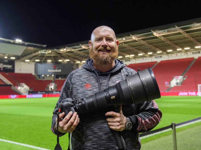 A profile picture of Chris Vaughan, owner of Chris Vaughan Photography at the side of a football pitch.